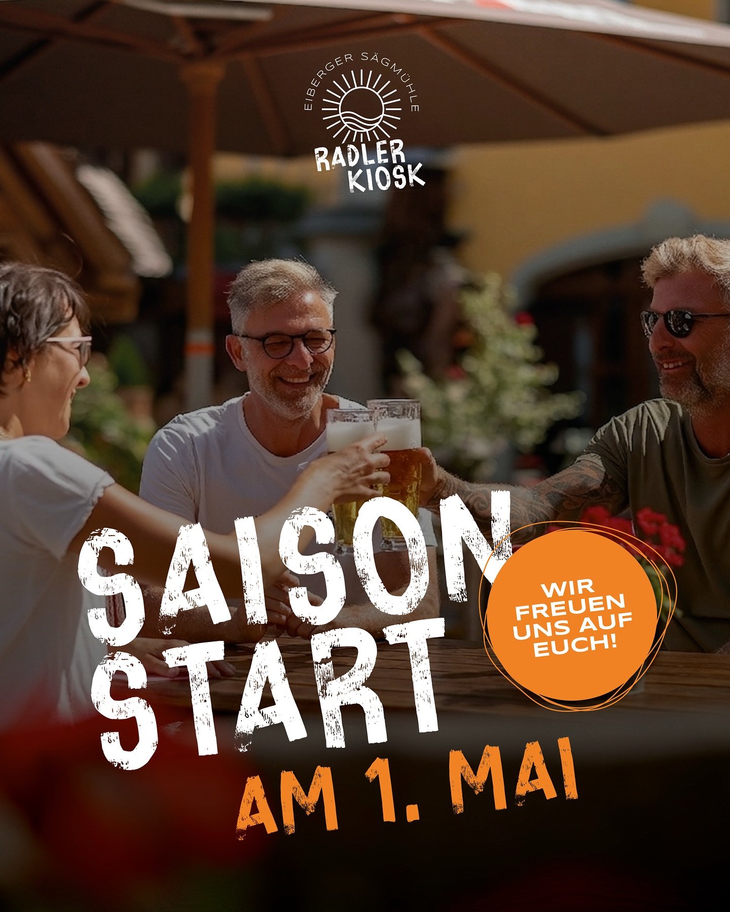 Gäste stoßen im Biergarten mit Biergläsern an